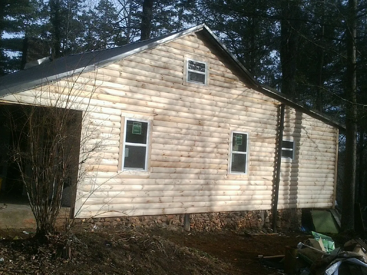 New log siding and dark metal roofing on a gable end in Irvona
