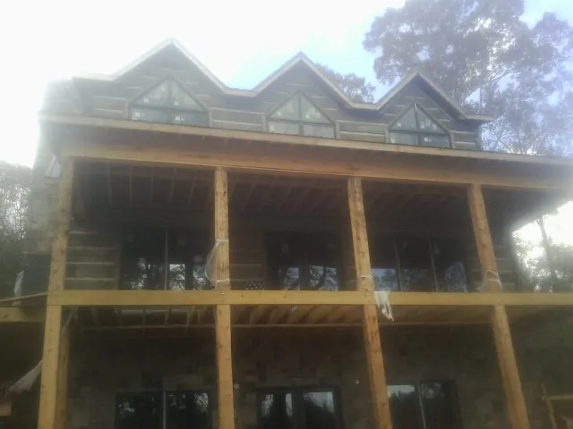 Dormers and porch framing on a large log home under construction — Roof Coating work by our crew in Irvona