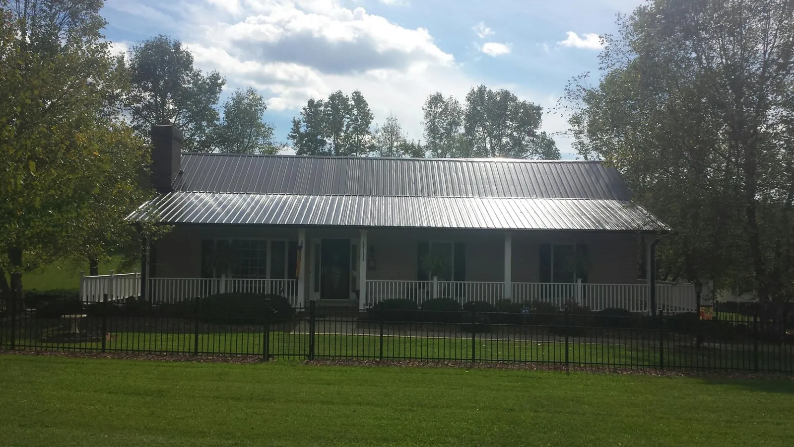 Gray metal roof on a brick ranch with a full width front porch — Gutter Guard Installation work by our crew in Irvona