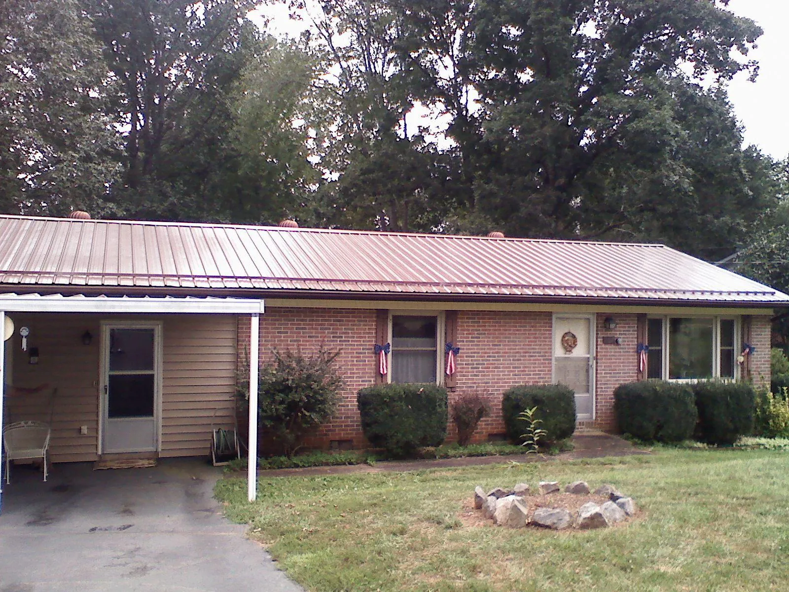 Bronze metal roof and carport on a brick ranch home — Roof Repair work by our crew in Irvona
